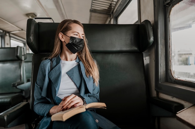 Passagier in de trein die medisch masker draagt en uit het raam kijkt