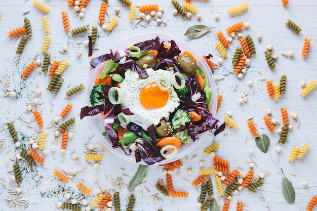 Gratis foto pasta en kruiden rond salade met gebakken ei