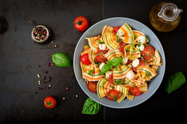 Pasta gekleurde farfalle salade met tomaten, mozzarella en basilicum.