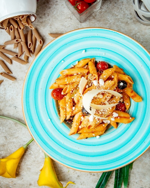 Gratis foto pasta in tomatensaus met olijven tomaat en geraspte parmezaanse kaas bovenaanzicht