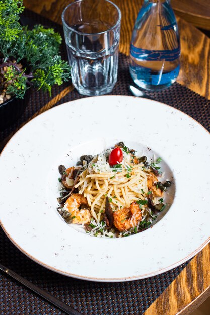 Pasta met garnalen, geraspte kaas, groenten en cherrytomaat op de top