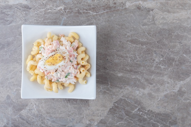 Pasta met gekookte eieren in witte kom.