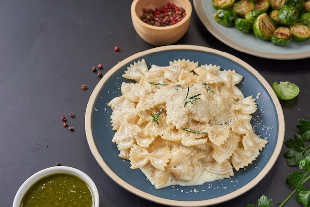 Gratis foto pasta met groene groenten en romige saus op een witte plaat. bovenaanzicht kopie ruimte. plat leggen.