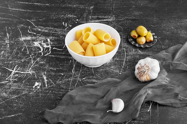 Gratis foto pasta met knoflook en olijven in een keramische kom.