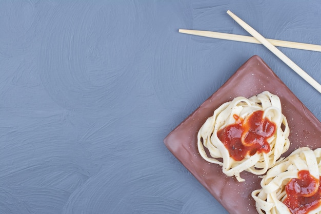 Pasta noedels met zoete chilisaus in een houten schotel.