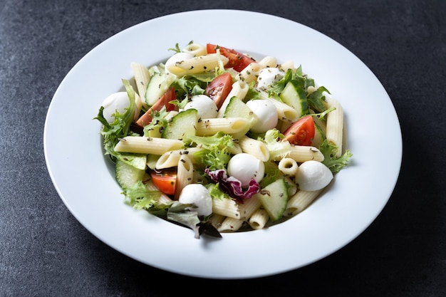 Gratis foto pasta salade met groenten en mozzarella kaas op zwarte achtergrond