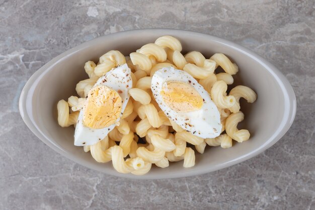 Pasta versierd met gekookt ei in keramische kom.