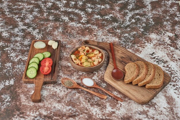 Pastasoep met kruiden en tomatensaus en groentesalade rondom.