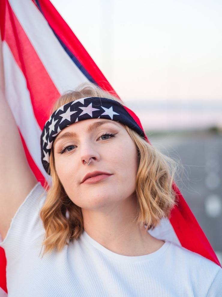 Gratis Foto patriottische blanke vrouw die een amerikaanse vlag vasthoudt terwijl ze midden op de weg staat