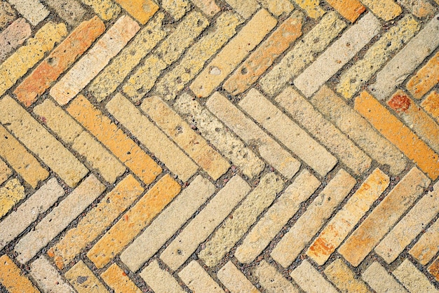 Patroon met rechthoekige gele baksteentegels in de vorm van een visgraat diagonale textuur abstracte achtergrond van oude bakstenen keramische geplaveide bovenaanzicht idee voor gemakkelijk bureaubehang
