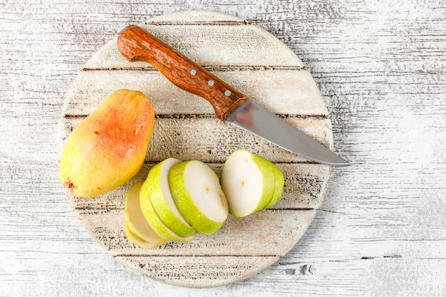 Peer en segmenten met mes bovenaanzicht op grungy en houten stuk achtergrond