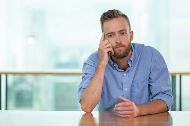 Peinzende jonge man zit op Empty Cafe Table