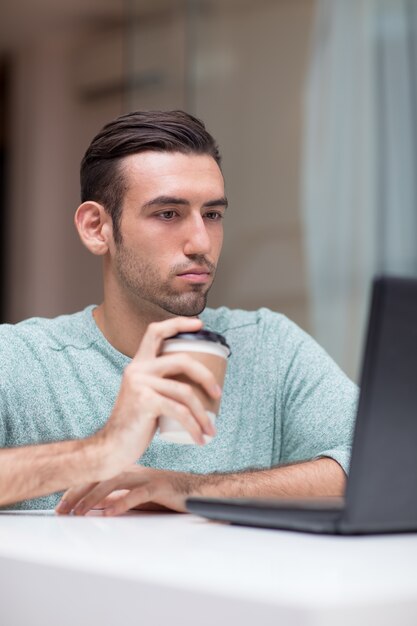 Peinzende knappe man die aan laptop thuis werkt