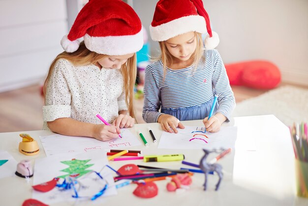 Peinzende meisjes die kerstschilderijen tekenen