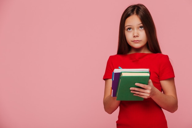 Peinzende meisjesleerling die exemplaarruimte bekijkt en boeken houdt