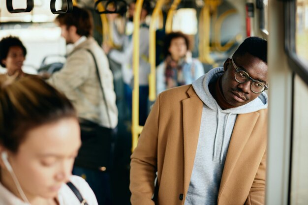 Peinzende zwarte man leunt op een raam terwijl hij met de bus reist