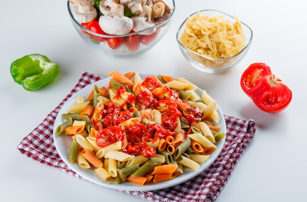 Penne pasta met champignons, tomaat, saus, peper, rauwe pasta in een plaat