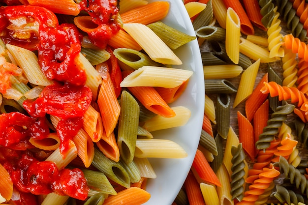 Penne pasta met saus, tomaat in een plaat op verspreide pasta