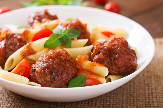 Pennedeegwaren met gehaktballetjes in tomatensaus in een witte kom