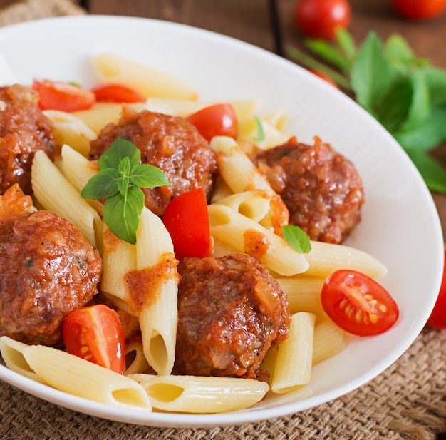 Pennedeegwaren met gehaktballetjes in tomatensaus in een witte kom