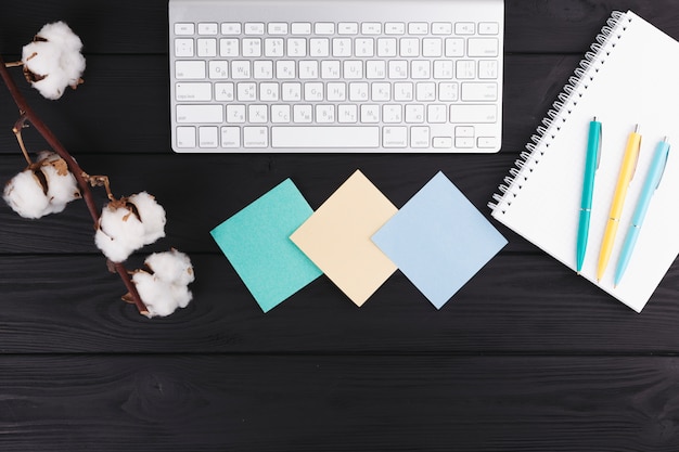 Pennen in de buurt van notebook, takje, papieren en toetsenbord