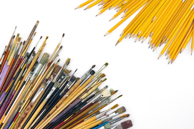 Gratis foto penselen gekleurd in verf en potloden op een witte achtergrond plat gelegd