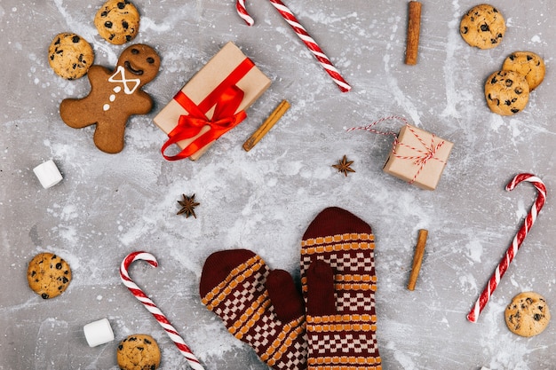 Peperkoek, koekjes, marshmallows, rood witte cnadies, kaneel, andere kruiden, huidige doos liggen rond warme handschoenen