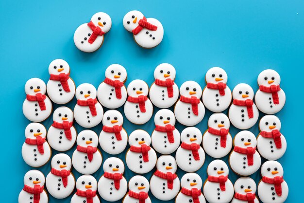 Peperkoeksneeuwpoppen bedekt met glazuur op een blauwe achtergrond plat gelegd