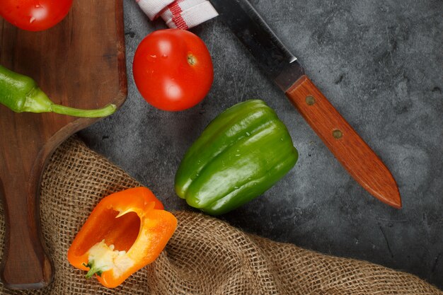 Pepers en tomaten op een stenen tafel met een mes. Bovenaanzicht