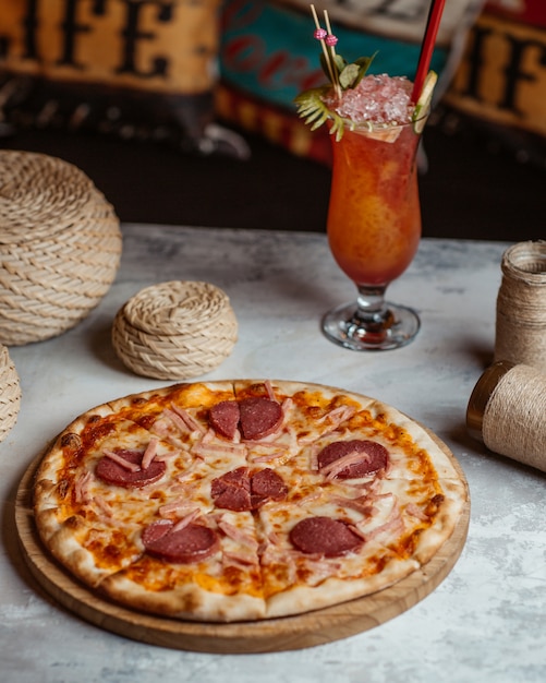 Gratis foto pepperonispizza op een houten raad met een glas cocktail.