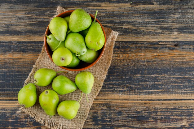 Peren in een kom op houten en stuk van zakachtergrond, hoogste mening.