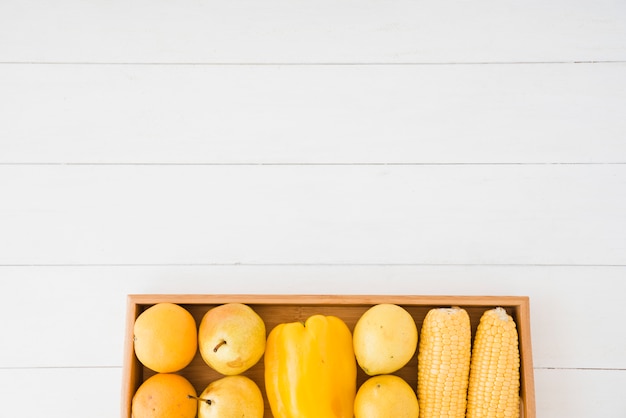 Peren; paprika en maïs op houten dienblad over de witte tafel