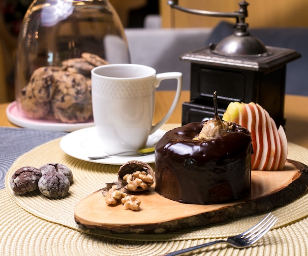 Perencake op de houten raad met okkernotenchocolade en vers fruit thee zijaanzicht