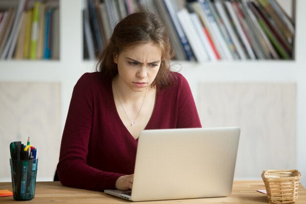 Perplex jonge casual vrouwelijke ondernemer laptop scherm kijken.