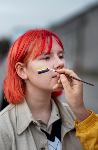 Persoon die buiten een niet-binaire vlag op een vriend schildert