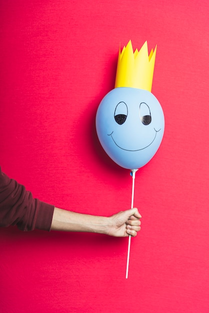 Persoon die een blauwe ballon op rode achtergrond met exemplaarruimte houdt