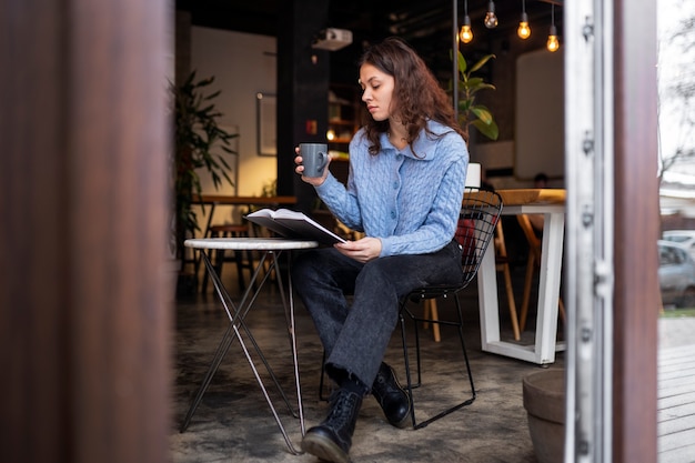 Gratis foto persoon die een boek leest in een café