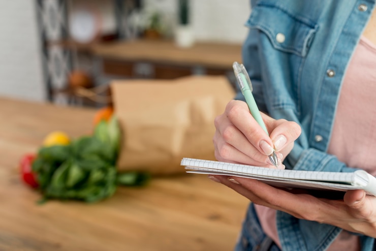 Gratis Foto persoon die een recept in het notitieboekje schrijft