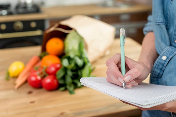 Gratis Foto persoon die een recept in het notitieboekje schrijft