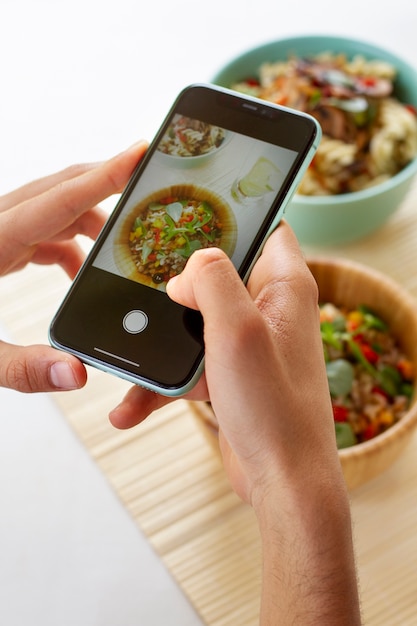 Persoon die foto maakt van kommen met eten met smartphone