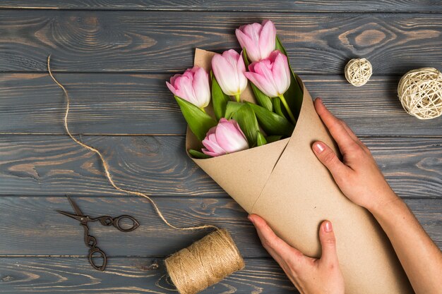 Persoon die heldere tulpen in pakpapier verpakken