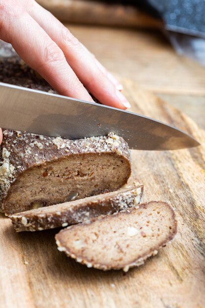 Persoon die rauw veganistisch brood snijdt met een mes