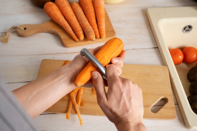 Gratis foto persoon die wortelen hakt in de keuken