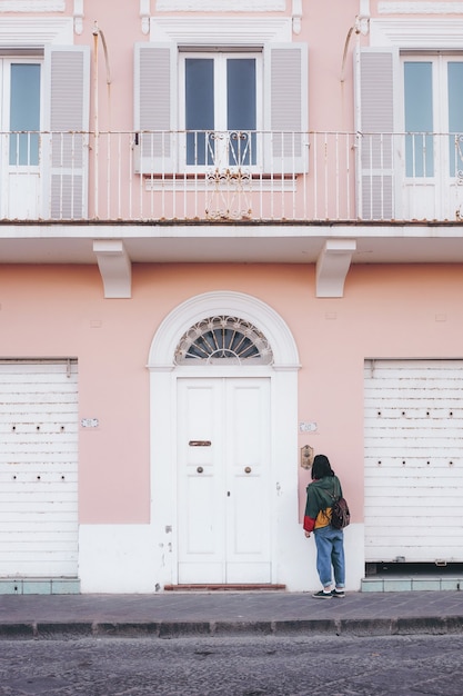 Persoon die zich voor roze en wit geschilderd gebouw bevindt