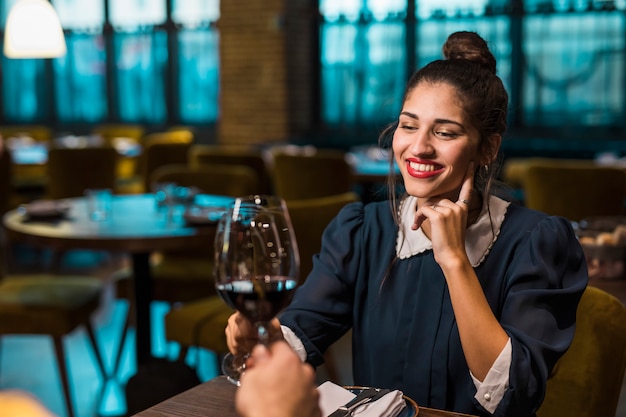 Persoon en gelukkige vrouw rinkelende glazen wijn aan tafel in het café