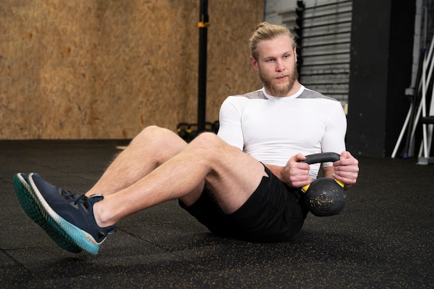 Persoon in sportgymnastiek die kettlebells gebruikt