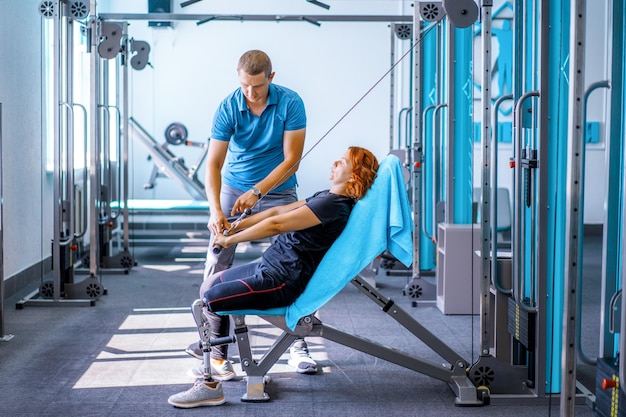 Gratis foto persoonlijke trainer die vrouw met een handicap helpt bij haar training. sportrevalidatiecentrum met fysiotherapeuten en patiënten die samenwerken aan genezing.