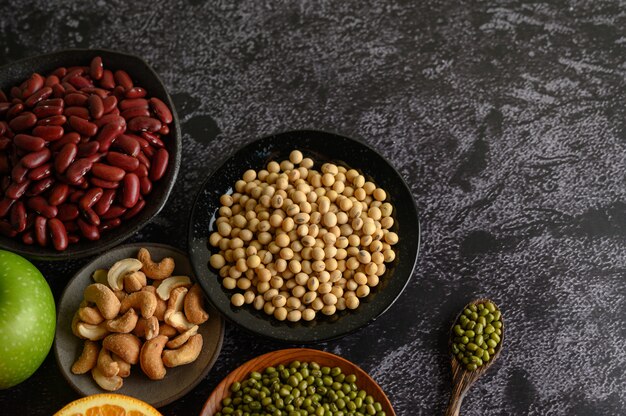 Peulvruchten en fruit op een zwart cement vloeroppervlak.