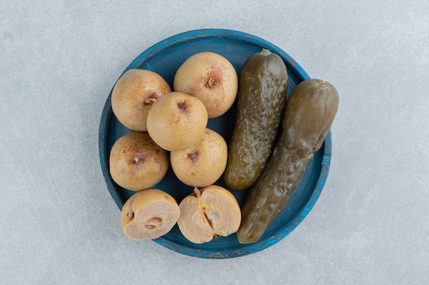 Pickles komkommer en appels op houten plaat op het marmeren oppervlak