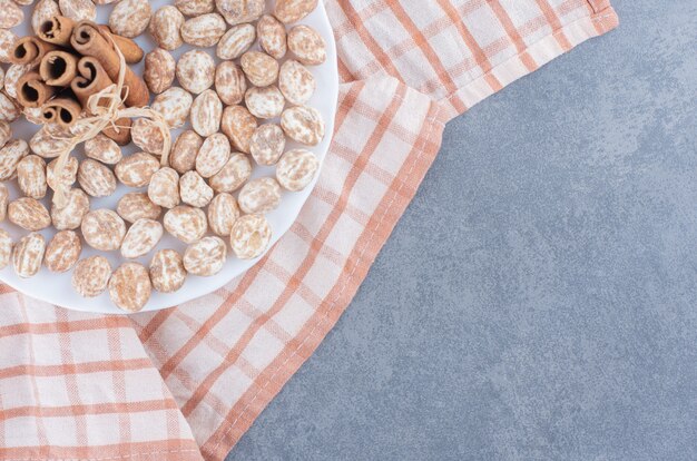 Pijpjes kaneel en koekjes op de handdoek, op de marmeren achtergrond.